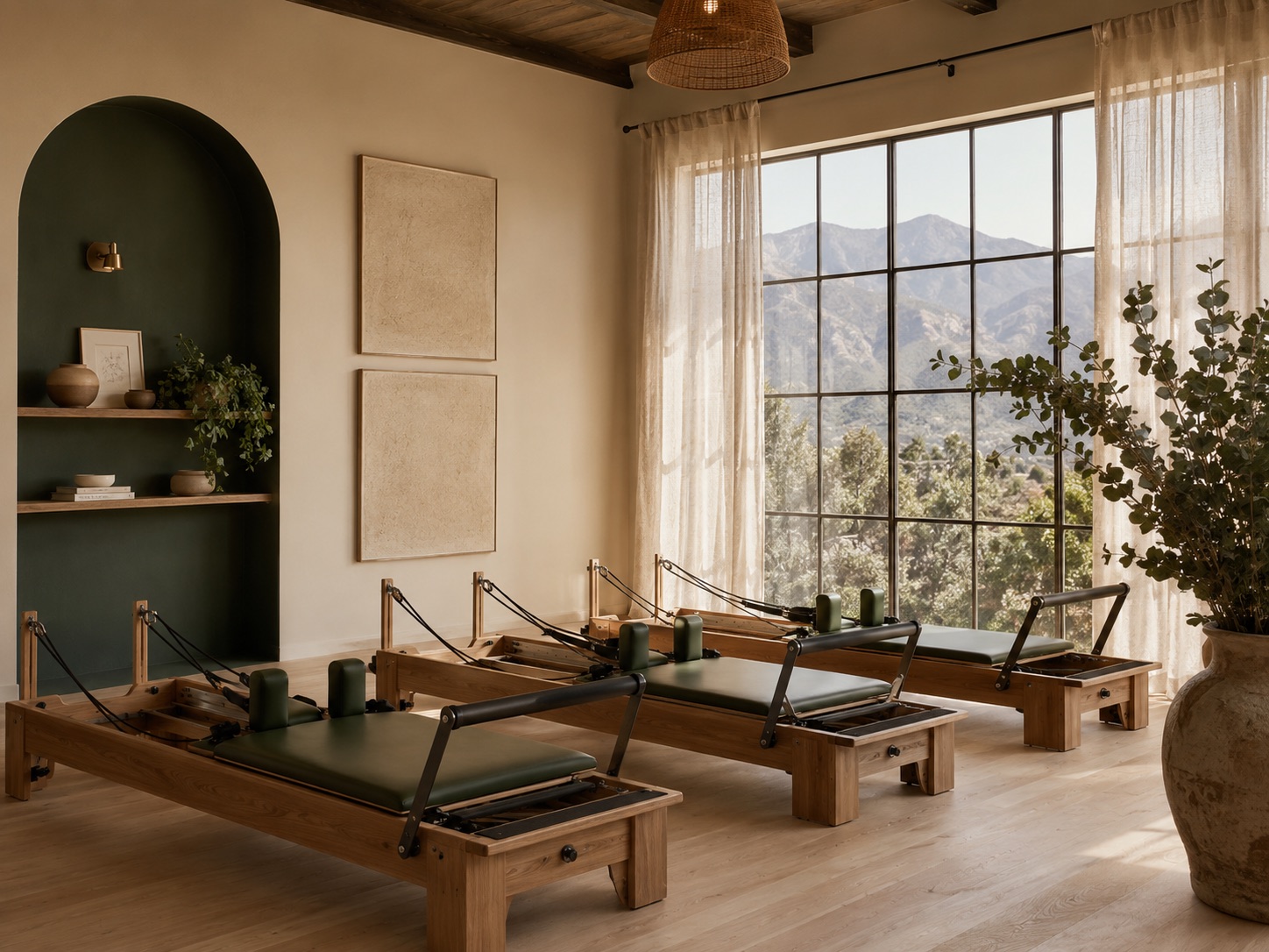 Three wooden reformers in a row beneath a mountain-view window